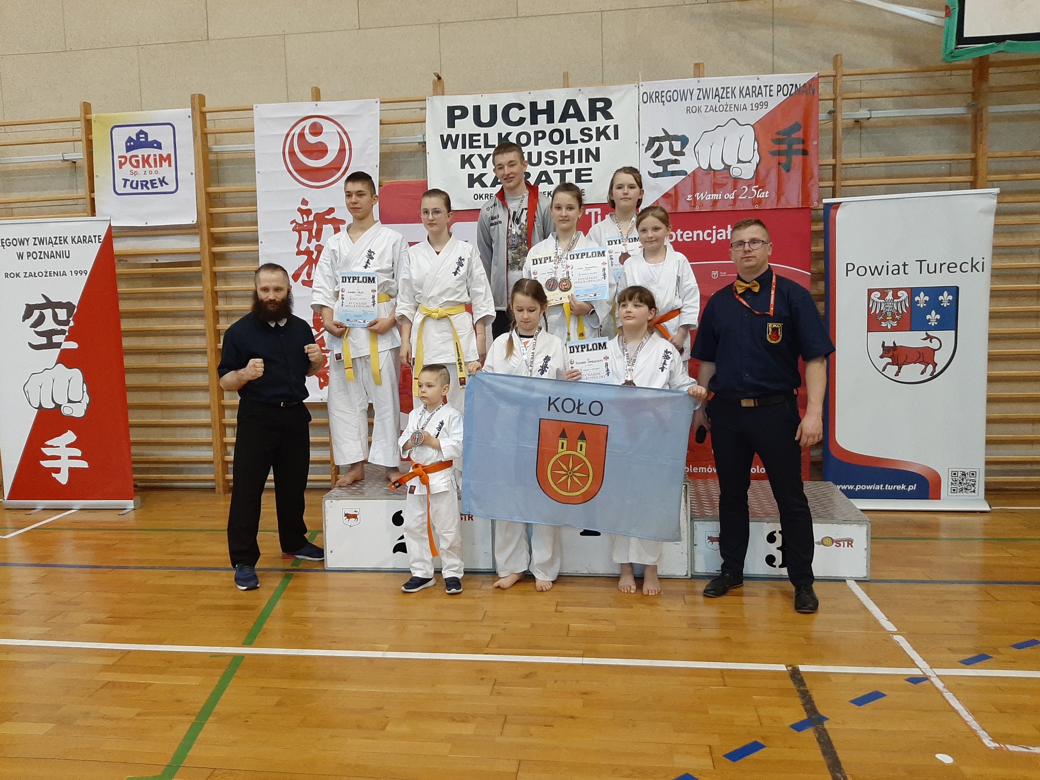Zawodnicy Kolskiego Klubu Karate Kyokushin na podium z medalami i flagą miejską Koła