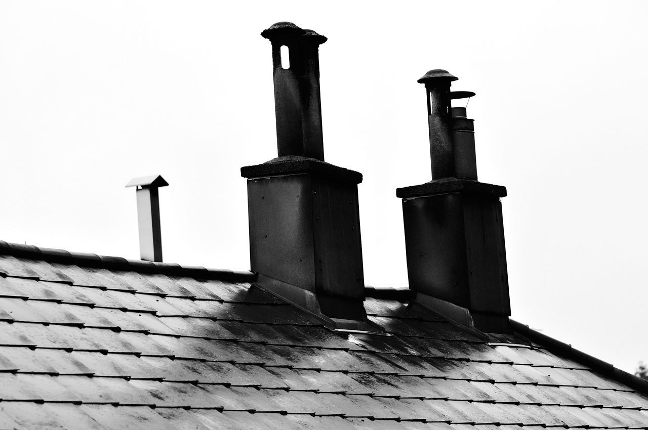 Zdjęcie przedstawia dwa kominy na dachu budynku