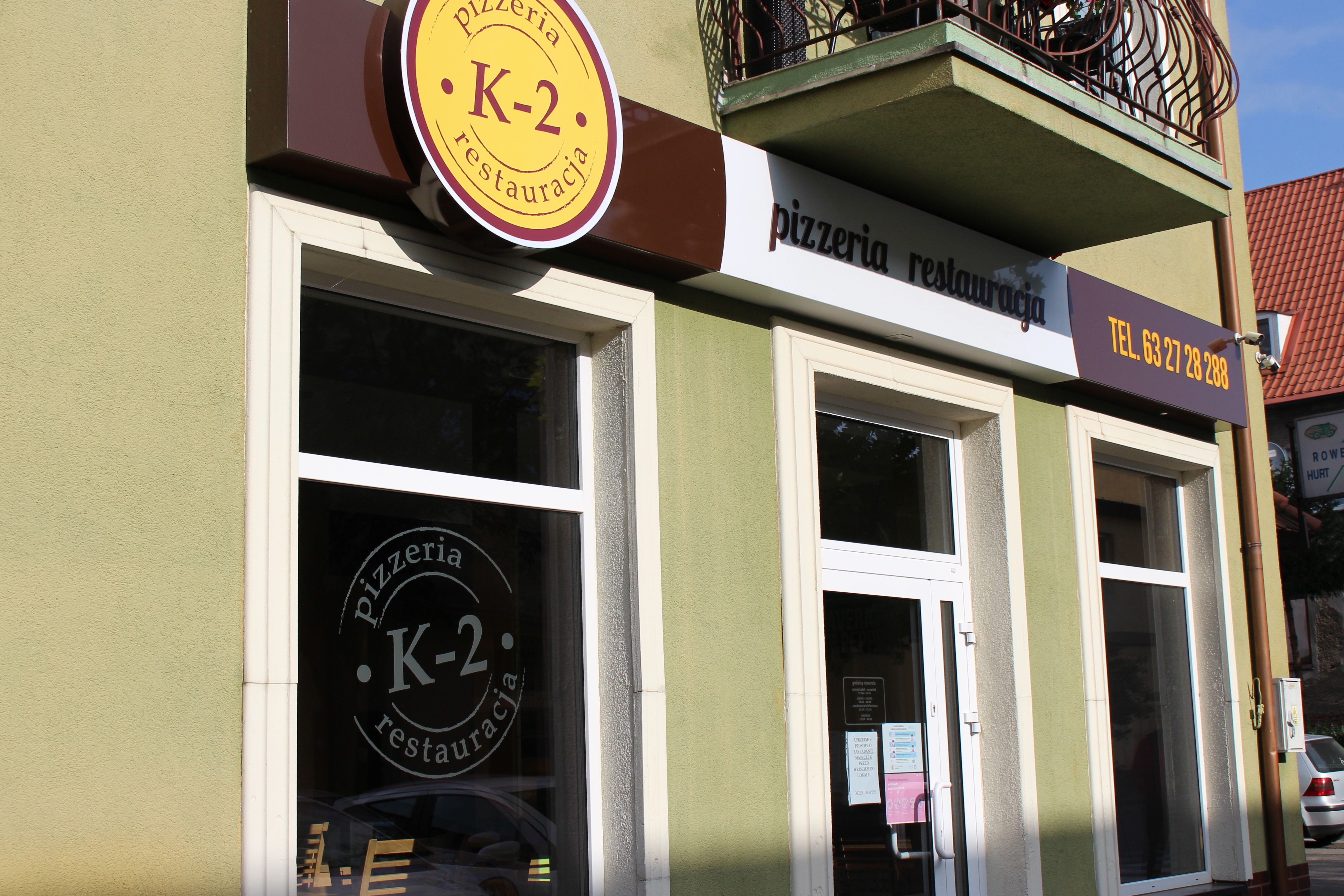 Zdjęcie przedstawia wejście do budynku pizzeri K2.