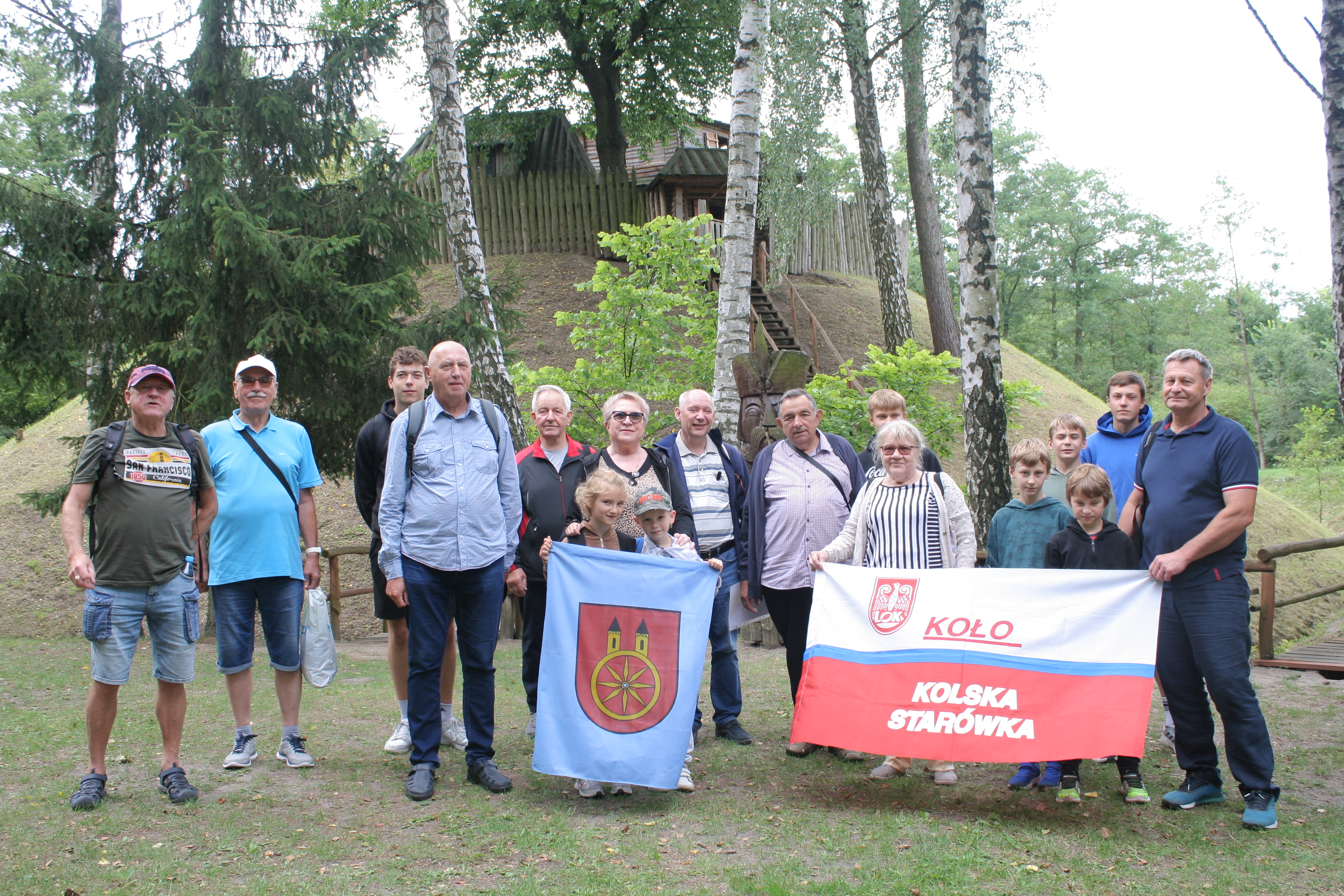 Na zdjęciu widać grupę osób pozujących z flagami miasta Koło i napisem 