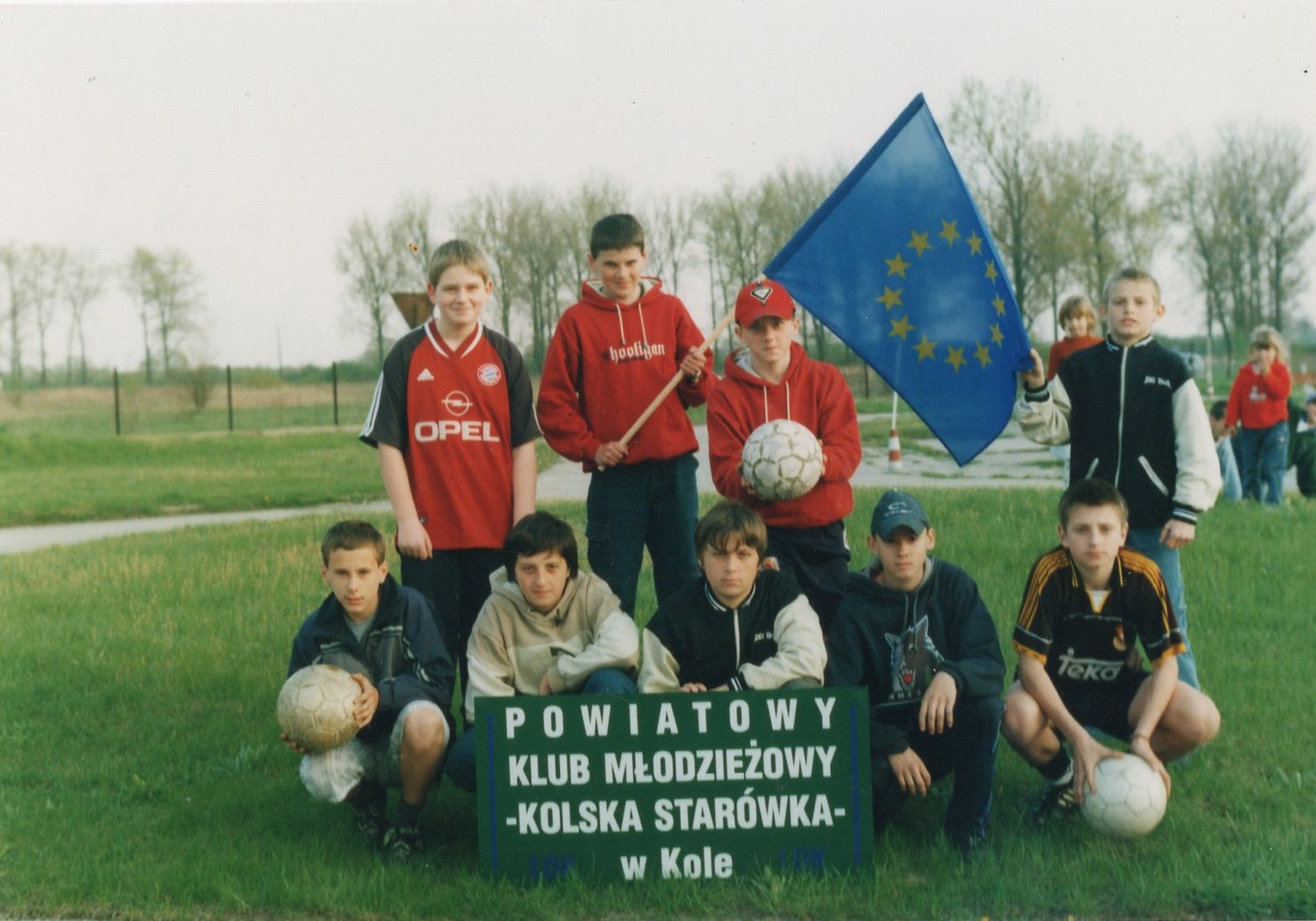 Drużyna chłopców w piłkę nożną Klubu LOK „Kolska Starówka” z flagą Unii Europejskiej