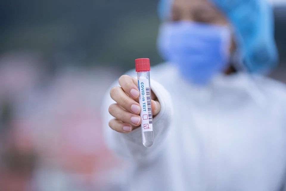 Zdjęcie przedstawia fiolkę w dłoni z napisem COVID-19 TEST.