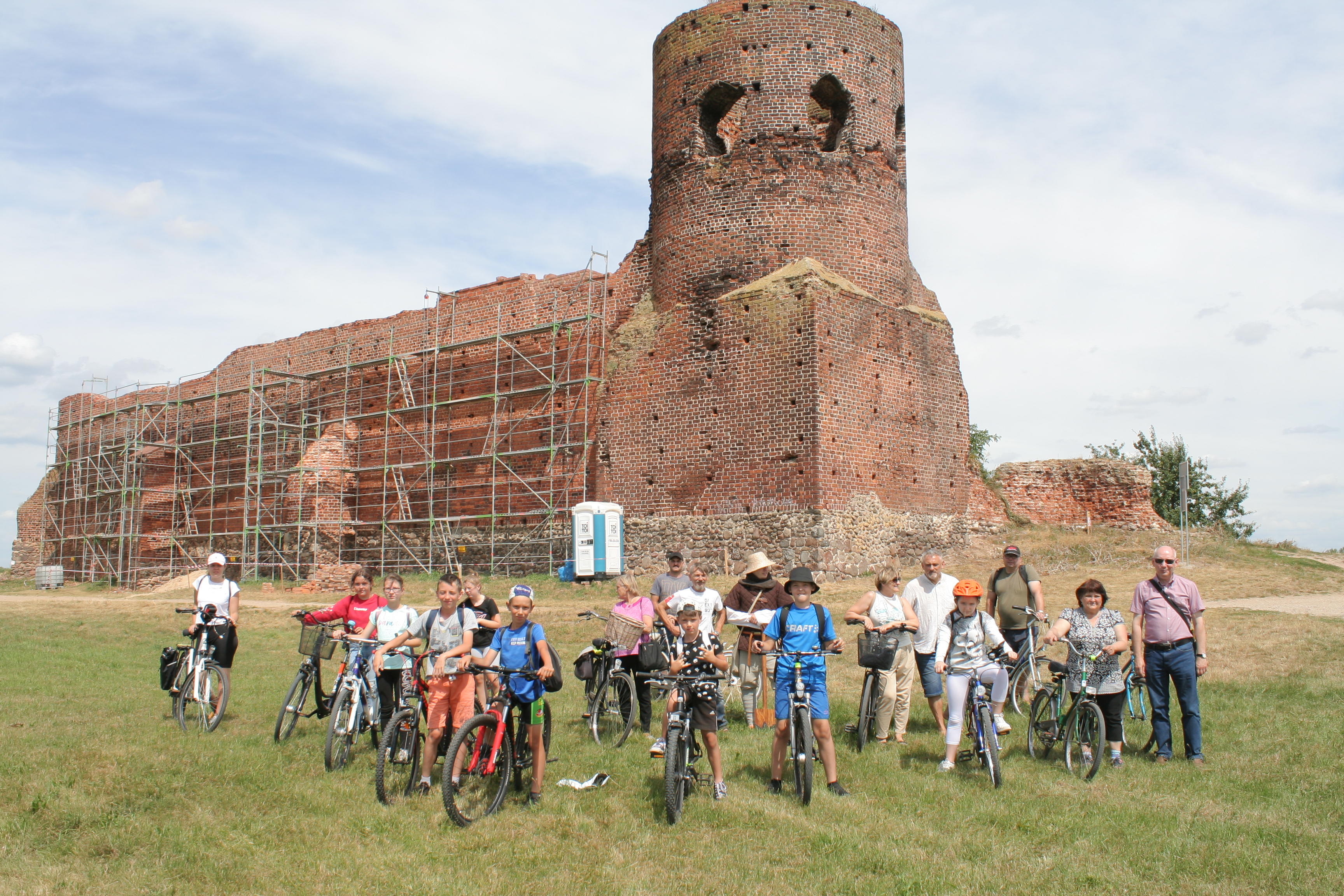 Uczestnicy rajdu rowerowego na tle ruin zamku w Kole