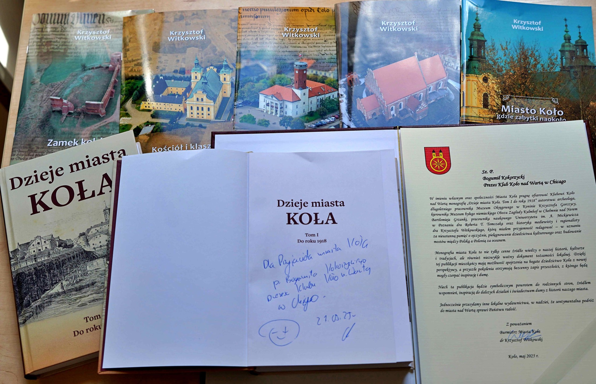 Zdjęcie przedstawia zestaw książek autorstwa Krzysztofa Witkowskiego o historii miasta Koła, w tym tom Dzieje miasta Koła oraz broszury o zabytkach. Obok znajduje się list z podziękowaniem dla prezesa Klubu Koło nad Wartą w Chicago.