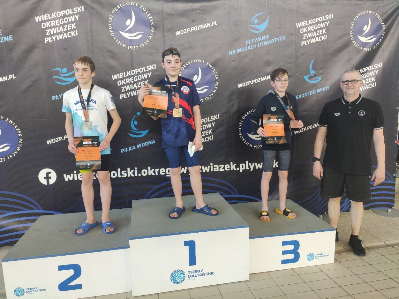 Zawodnicy na podium z medalami i dyplomami w dłoniach