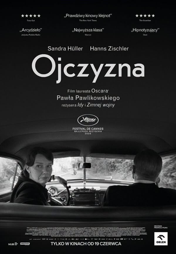 Czarno-biały plakat filmowy w pionie. Kadr z wnętrza auta widziany z tylnej kanapy: kobieta za kierownicą odwraca głowę w stronę siedzącego obok siwego mężczyzny. U góry cytaty recenzentów i gwiazdki, na środku biały tytuł Ojczyzna.