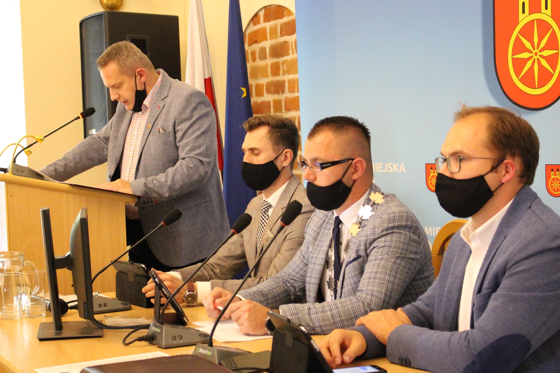 Zdjęcie przedstawia Burmistrza przy mównicy oraz Przewodniczącego oraz w-ce przewodniczących RM.