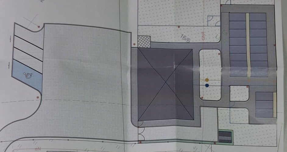 Zdjęcie przedstawia plan zagospodarowania terenu z budynkami, drogami dojazdowymi i miejscami parkingowymi, w tym jednym miejscem dla osób z niepełnosprawnościami.