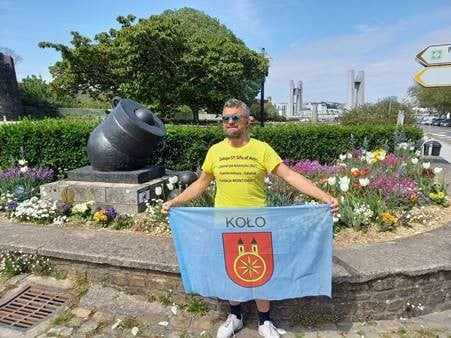 Pan Darek stoi z flagą miasta Koła