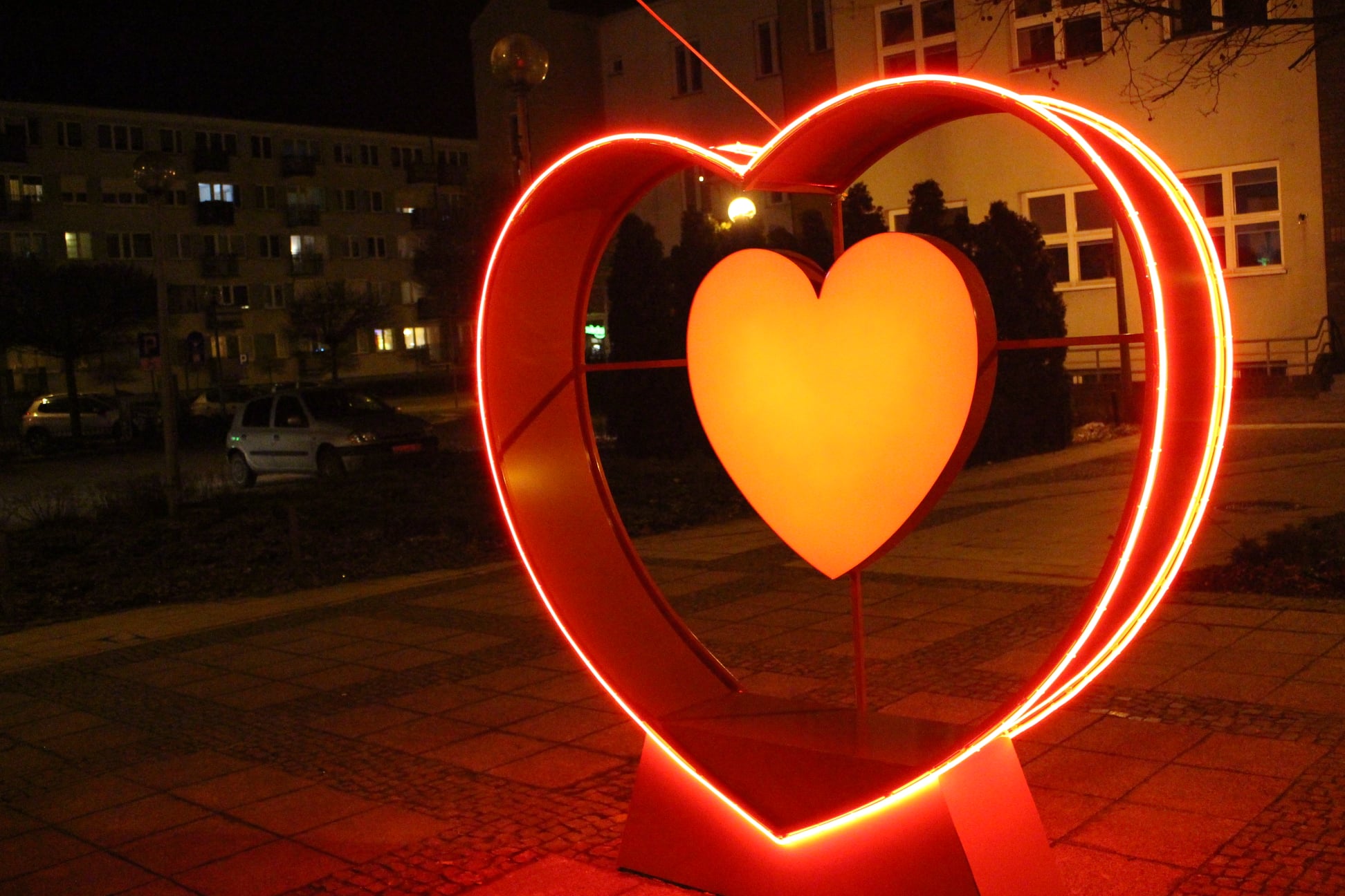 Zdjęcie przedstawia czerwone neonowe serce z wymiennym wewnętrznym kasetonem przed US w Kole.