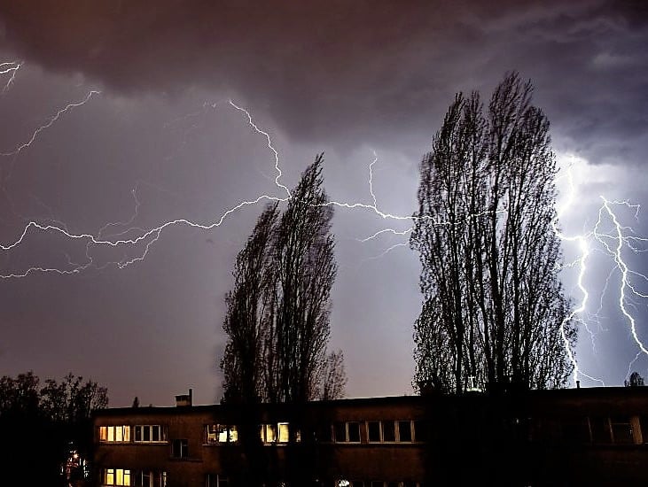 Zdjęcie przedstawia błyskawice nad budynkami.