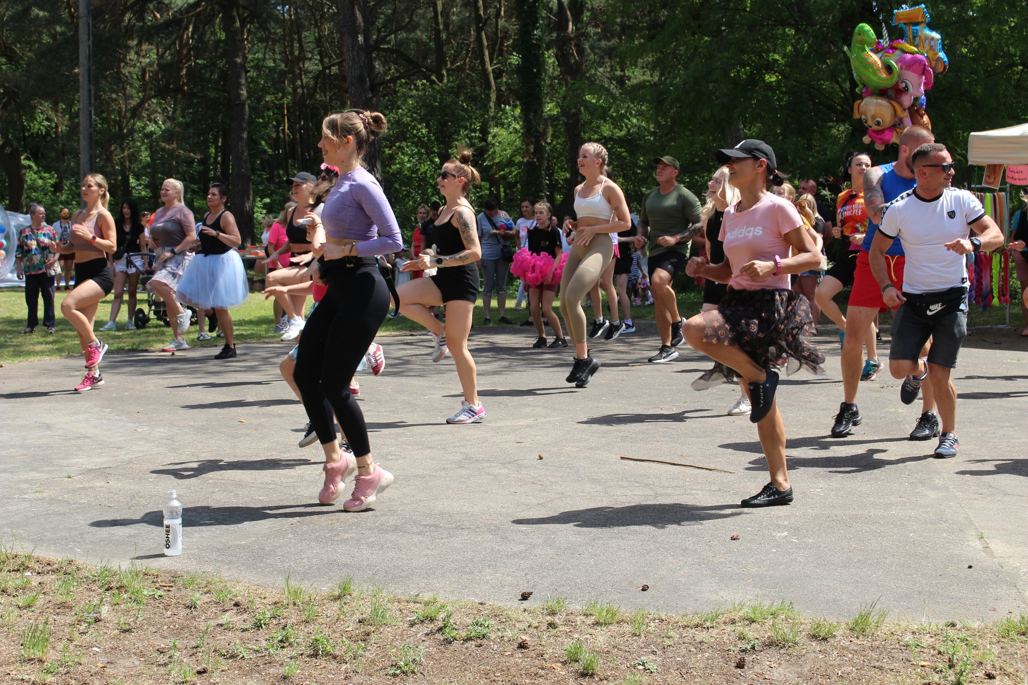 Tańcząca grupa osób podczas Charytatywnego „Wiosennego Biegu Księżniczek” w kolskim parku