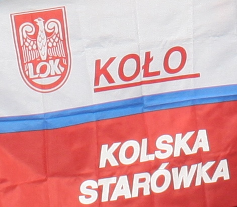 Flaga w barwach biało-czerwonych. W górnej białej części czerwone godło Ligi Obrony Kraju (LOK) z orłem oraz czerwony podkreślony napis KOŁO. W dolnej czerwonej części biały napis KOLSKA STARÓWKA. Poziomy niebieski pasek oddziela obie części.