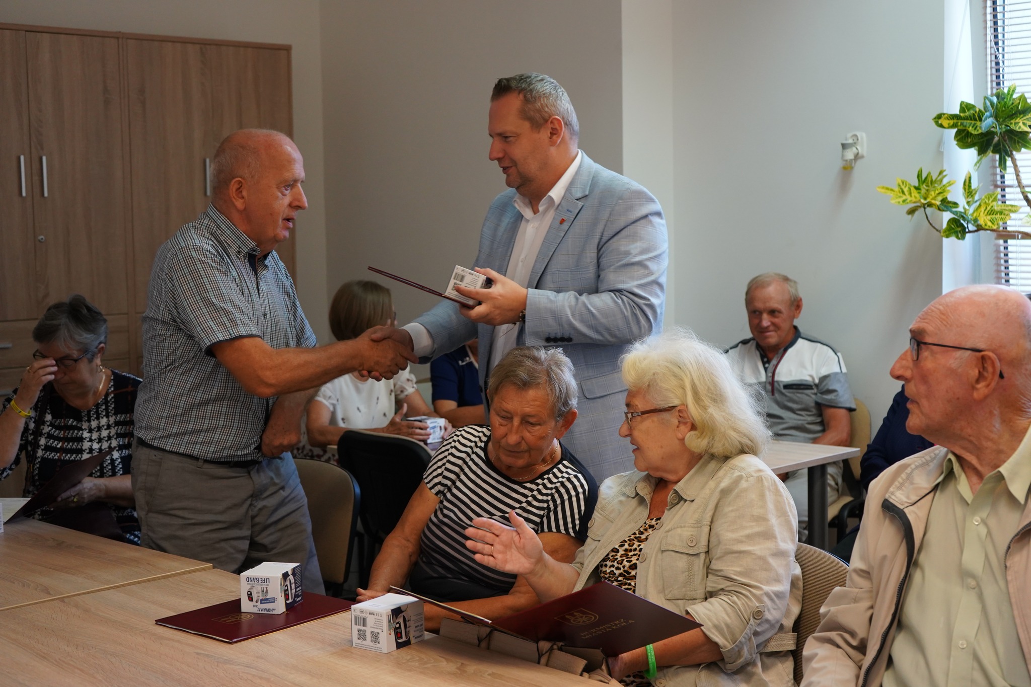Burmistrz Miasta Koła Krzysztof Witkowski wręcza opaski bezpieczeństwa kolskim seniorom