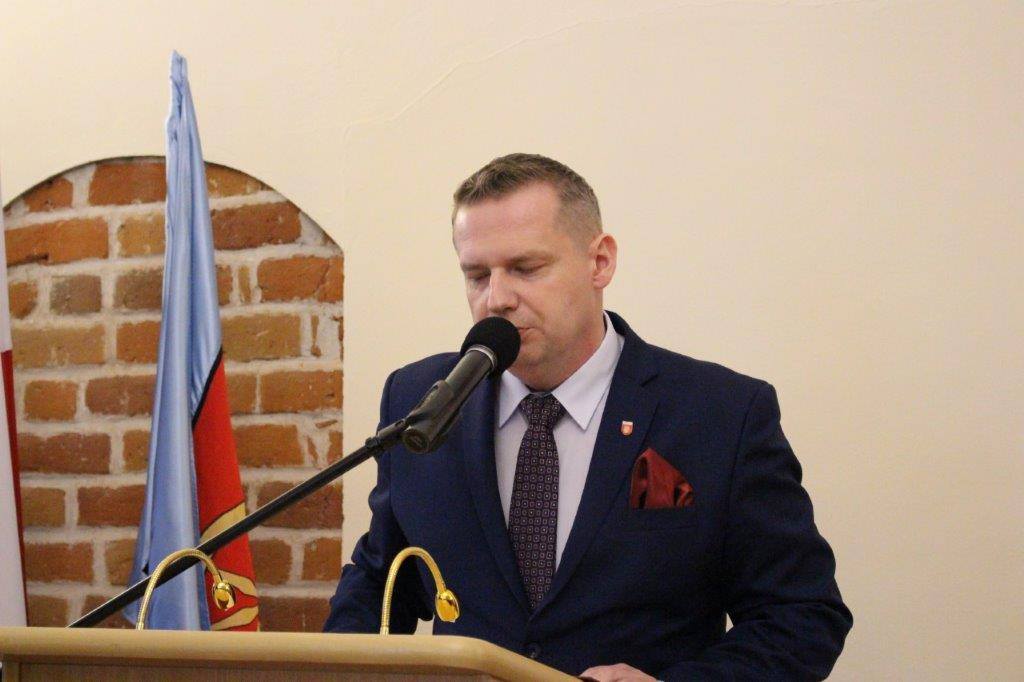 Zdjęcie przedstawia Burmistrza Miasta Koła na mównicy w sali sesyjnej Ratusza.